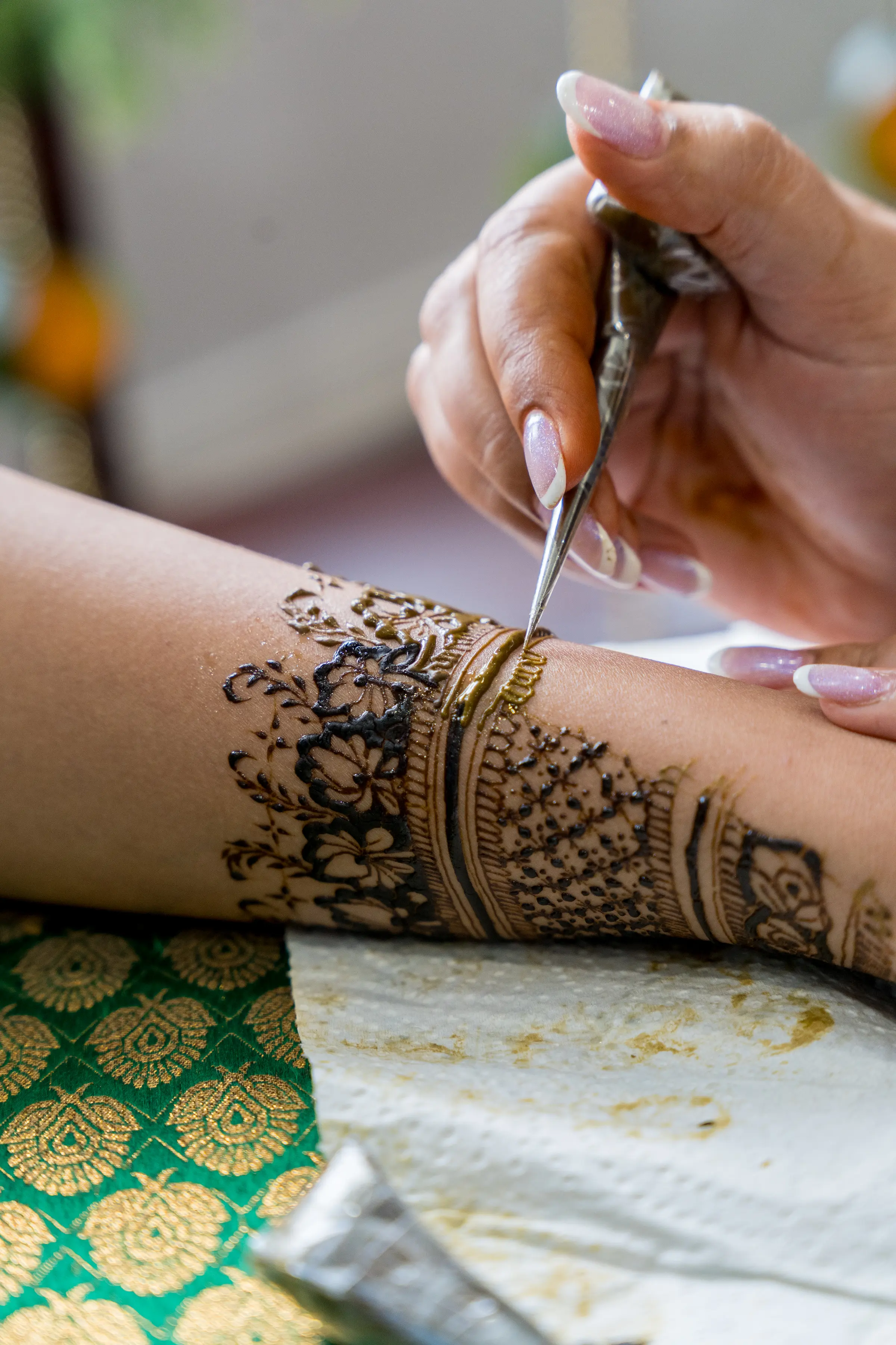 An artist draws mehendi onto an outstretched arm.