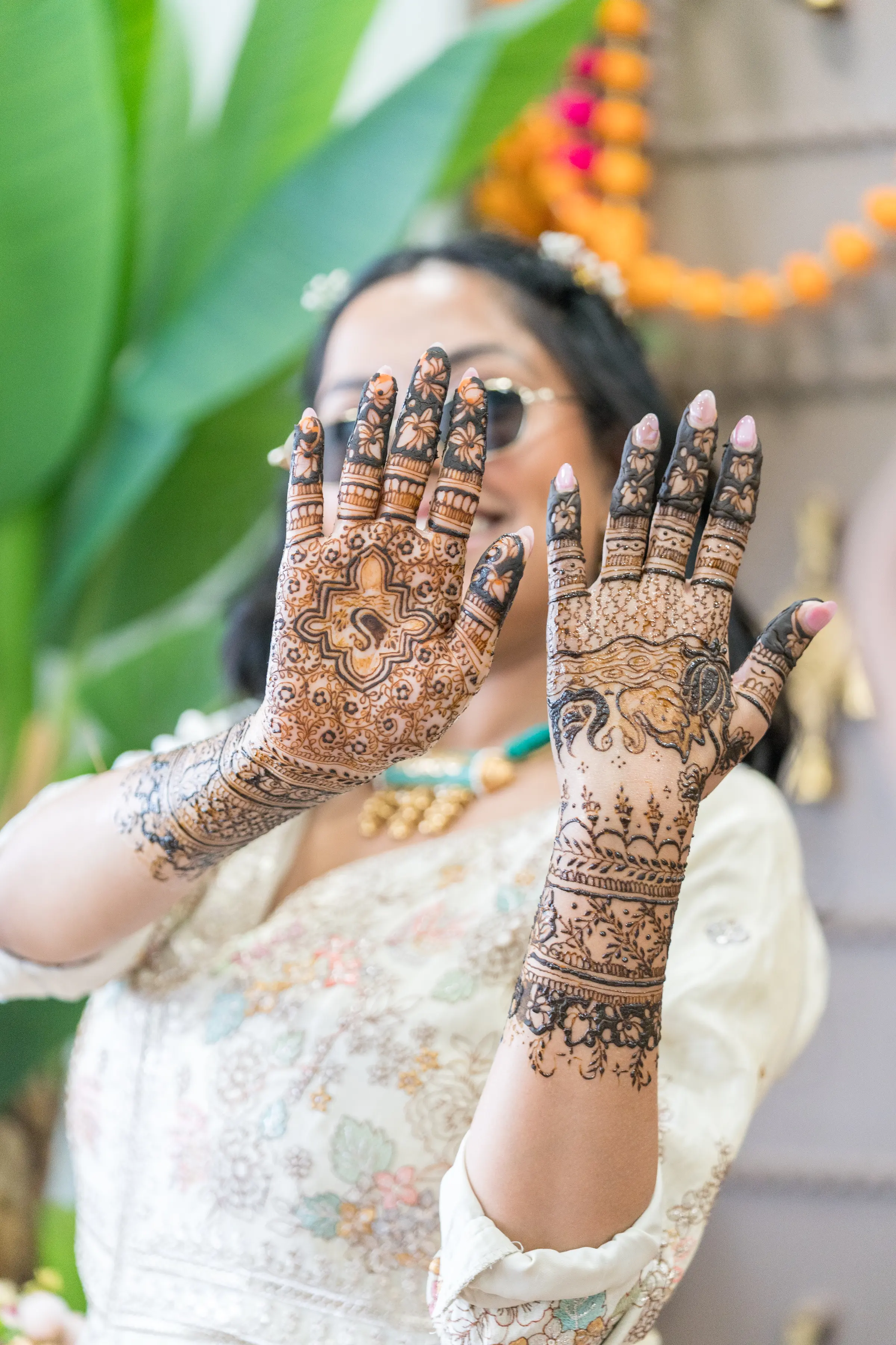 A woman raises both hands to show freshly finished mehendi.