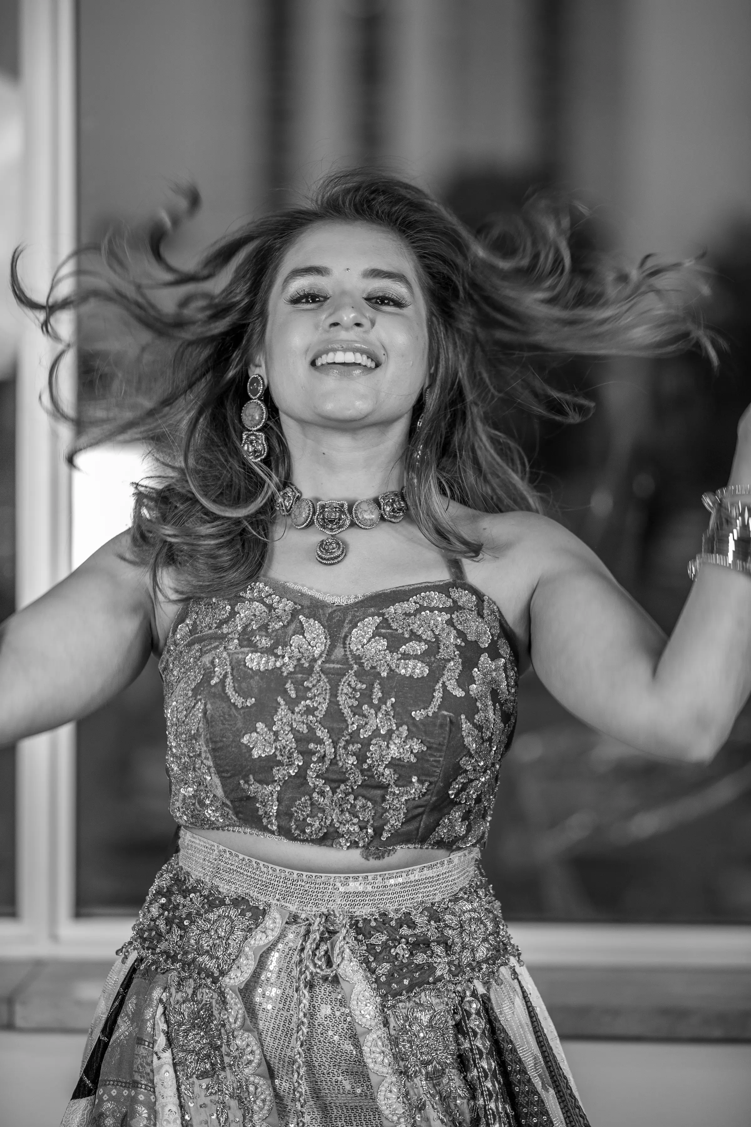 A portrait in motion, hair caught mid-turn, laughing, in black and white.