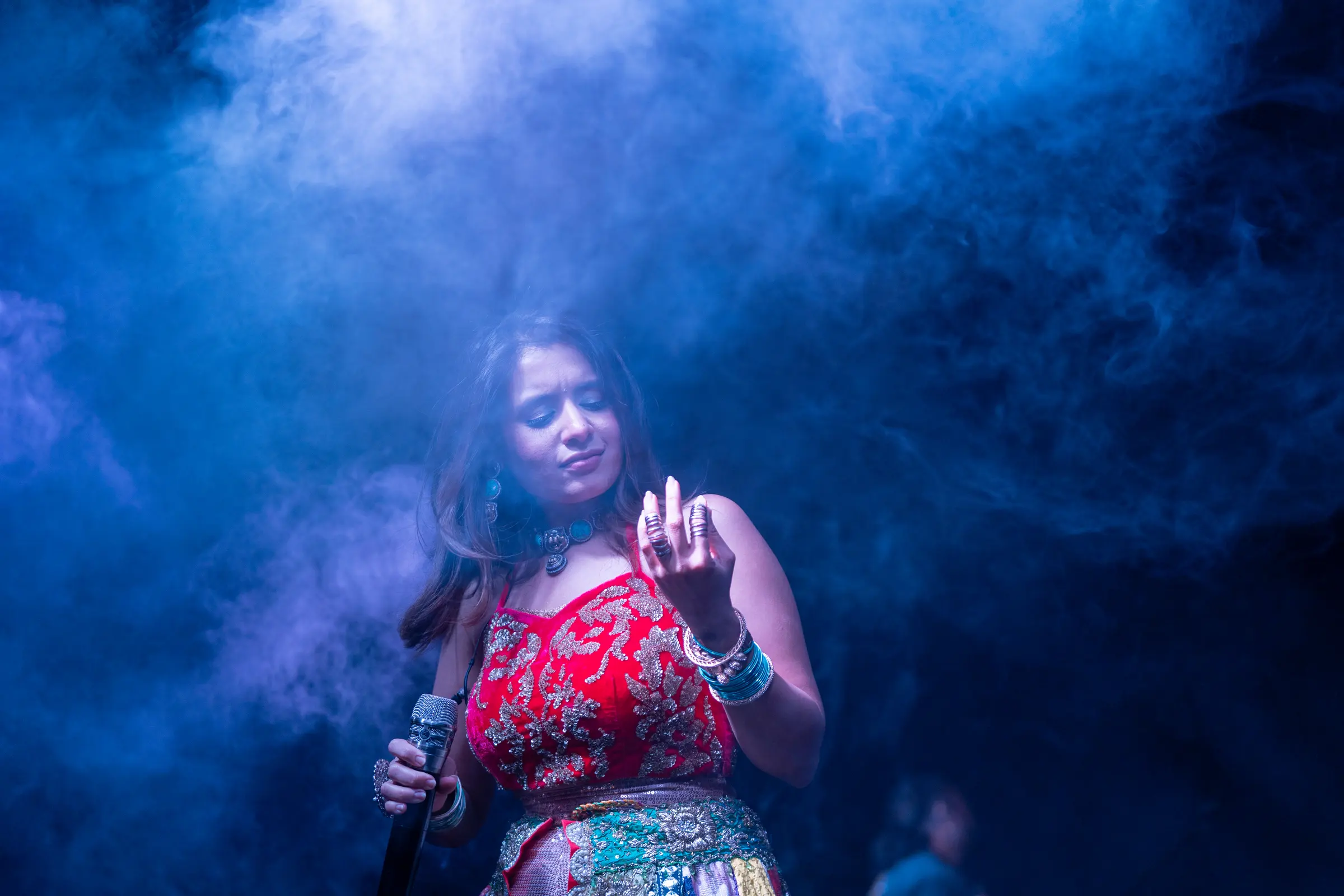 A singer on stage lit through blue smoke.