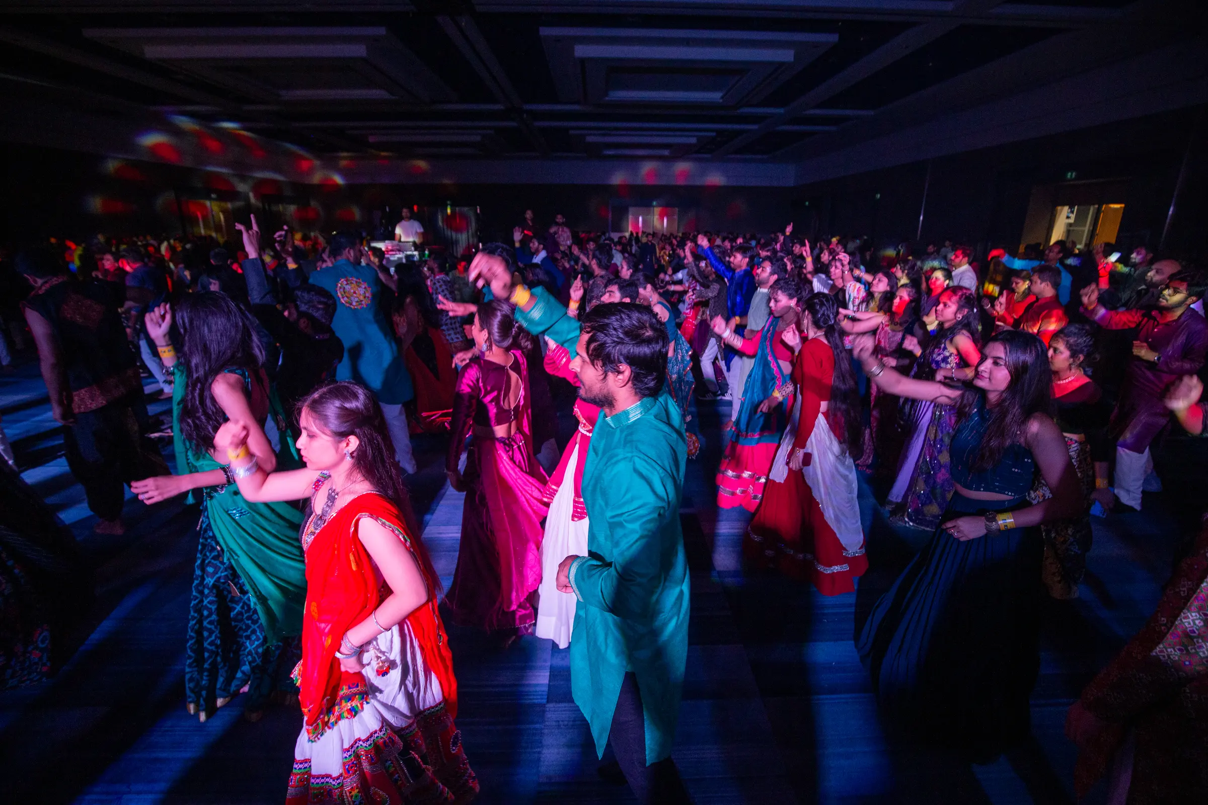 A packed dance floor caught in motion under red and blue light.