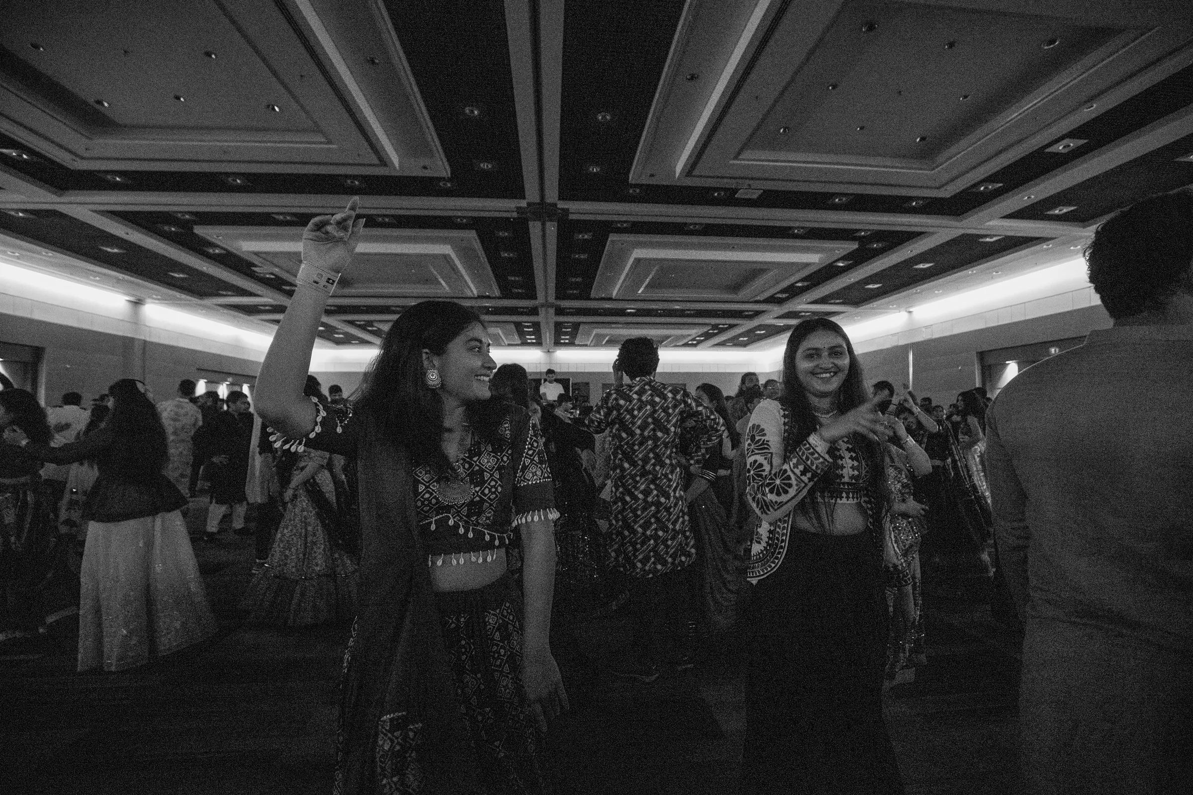 A crowd dancing garba under ballroom lights, shot in black and white.