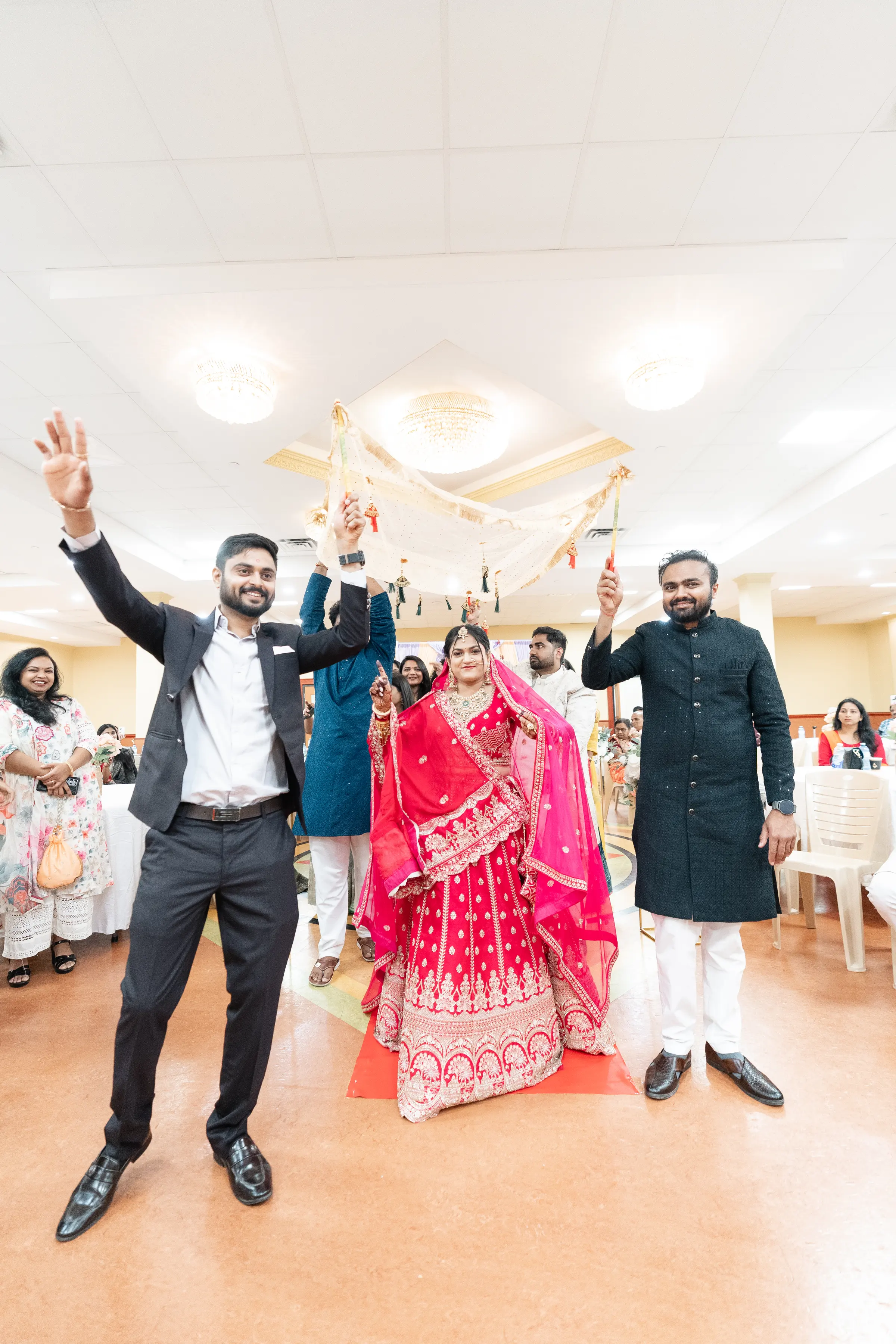 A groom raises his arms as guests dance around him.